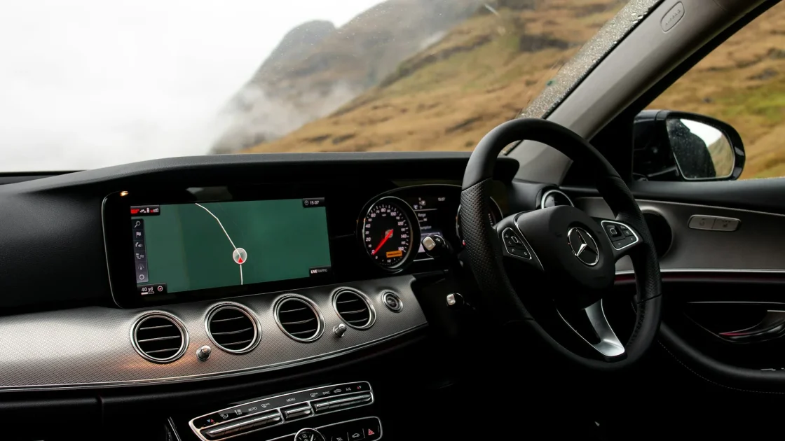A modern car dashboard displaying active driver-assist safety features while driving.