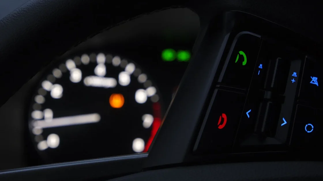 A close-up of a car instrument cluster with an amber driver-assistance warning symbol still illuminated.