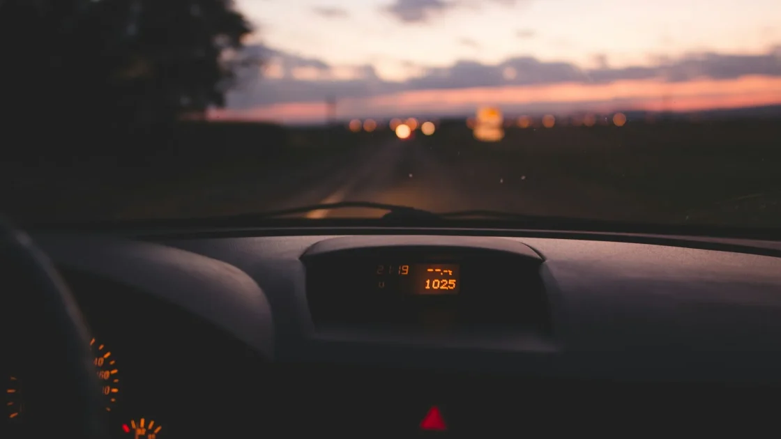 An amber steering wheel warning symbol glowing on a car instrument cluster next to the speedometer.
