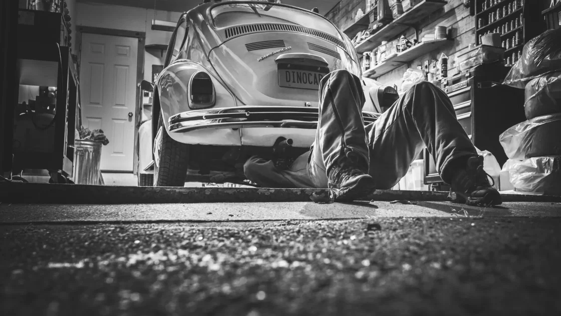 A mobile technician setting up ADAS calibration equipment beside a car parked in a residential driveway.