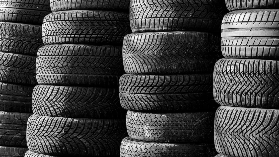 Close-up of a car tire sidewall showing the size code and tread, mounted on an alloy wheel.