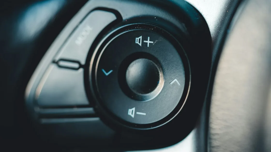 Close view of steering wheel cruise control buttons with a cruise control unavailable message on the dashboard.