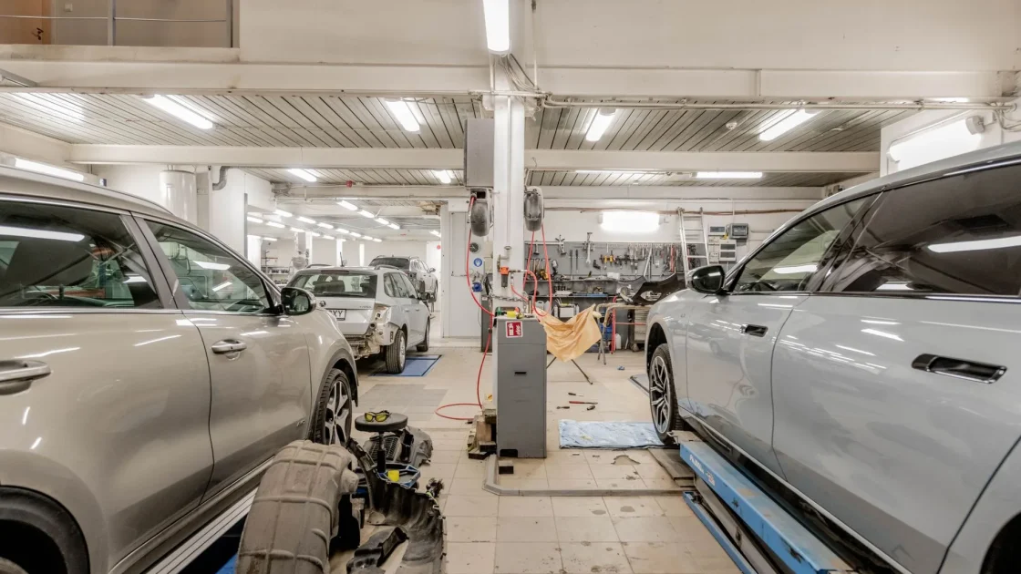 A technician positioning a calibration target board in front of a car inside a service bay.