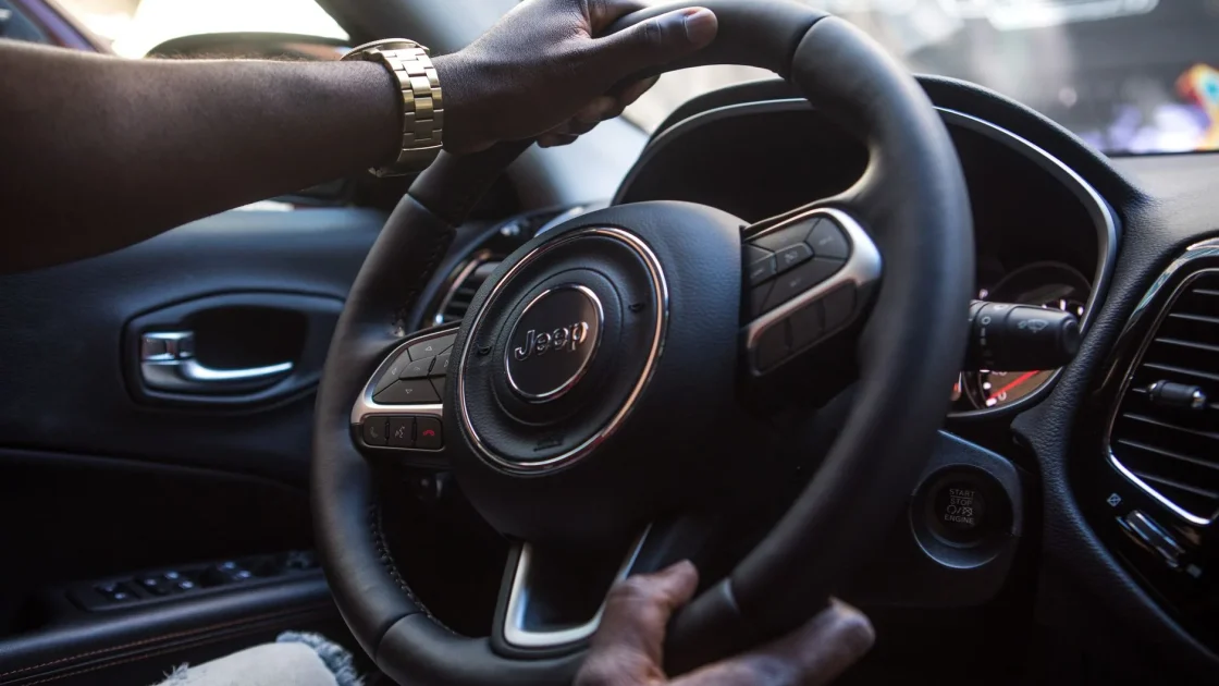 A driver's hands resting lightly on the steering wheel while a lane-centering display glows on the dashboard.