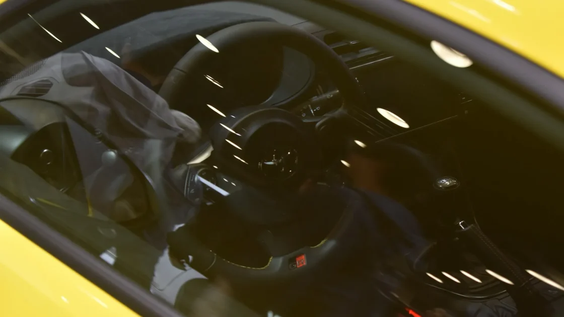 Close-up of a forward-facing ADAS camera housing mounted behind a car's rearview mirror on the windshield.