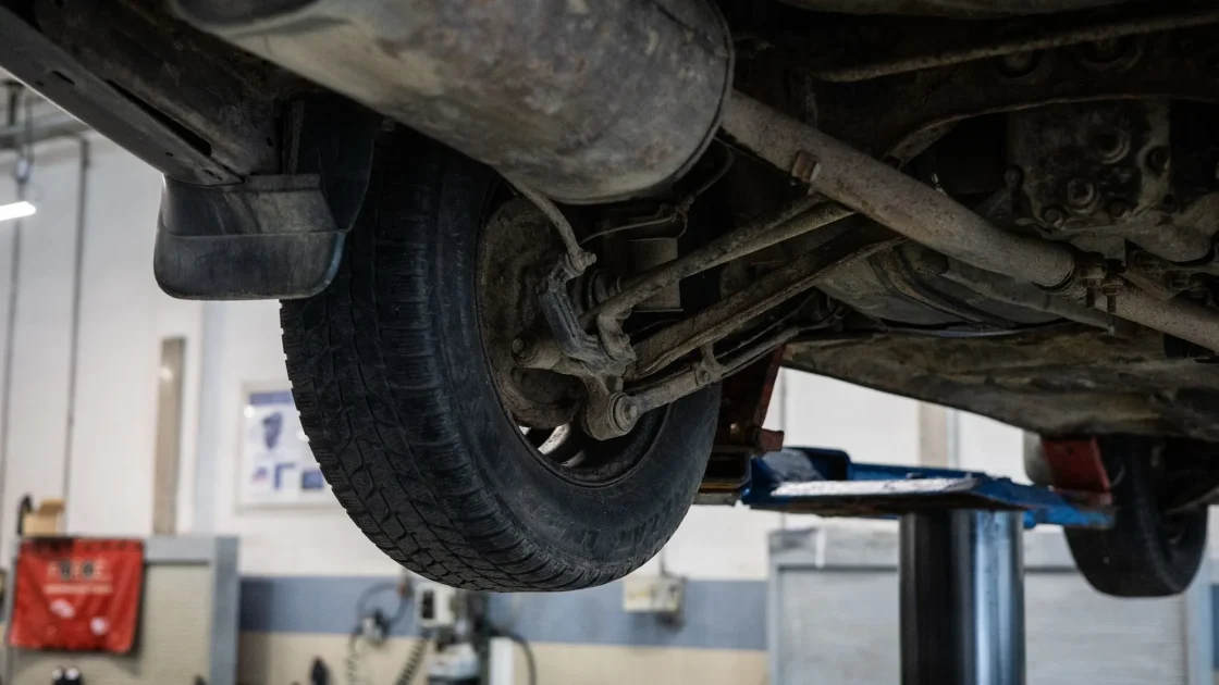 A car raised on a lift with a new tire and visible suspension components during service work.