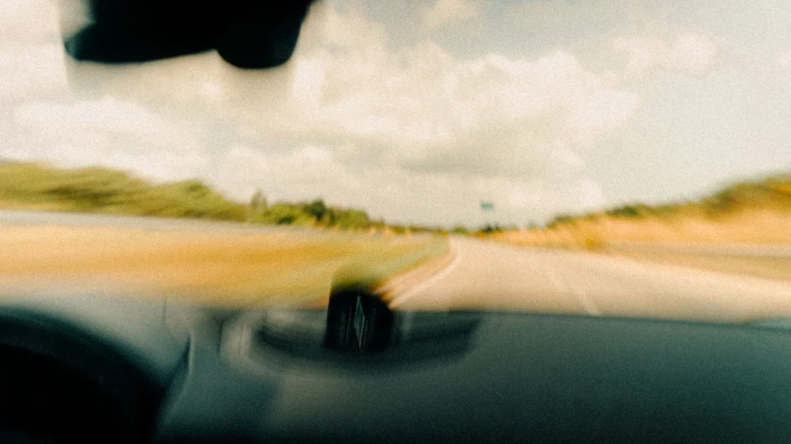 A forward ADAS camera behind a car windshield viewing the road ahead through the glass.