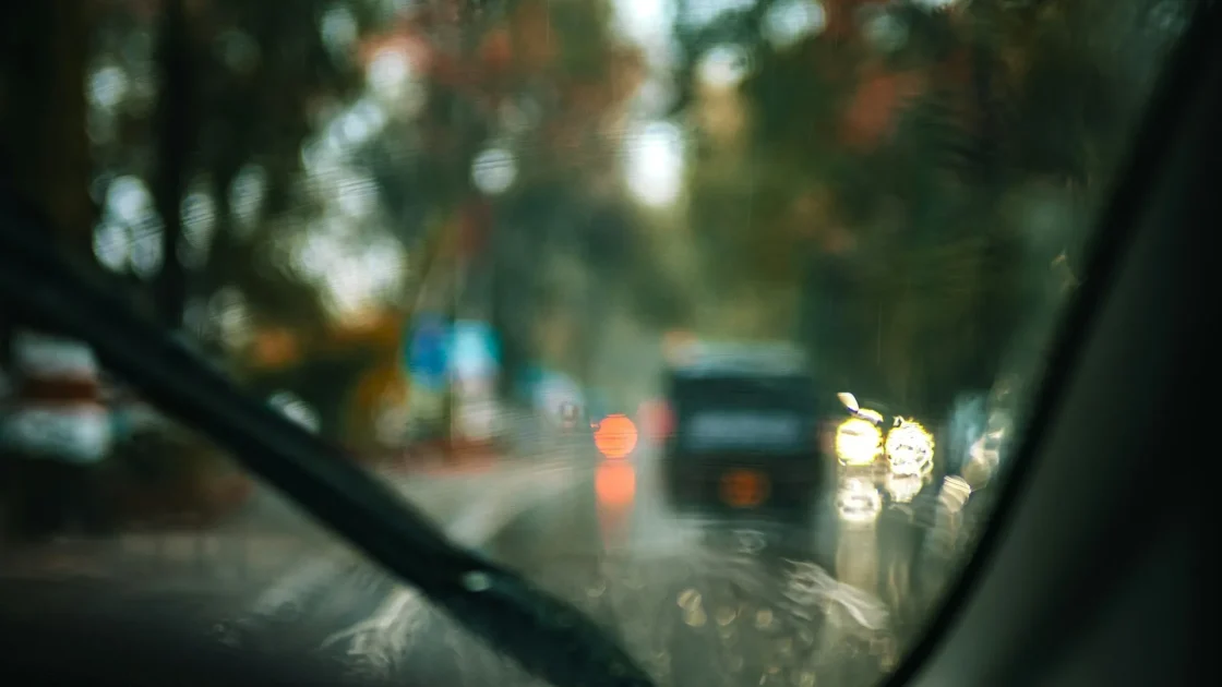 A rain-soaked windshield with wipers running, seen from the driver seat during a heavy downpour.