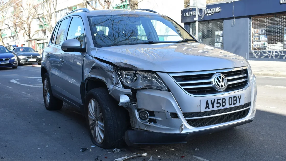 A car with its front bumper cover removed showing the radar sensor and mounting bracket behind it.