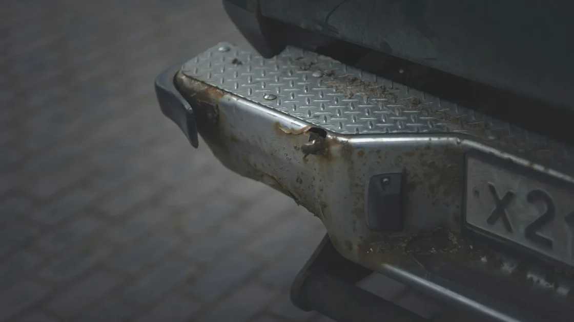The rear corner of a car in a parking lot with a hidden radar sensor behind the bumper watching for cross traffic as the car reverses.