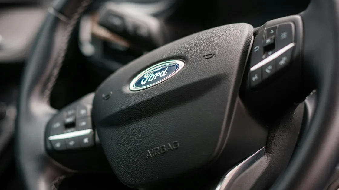 A car steering wheel showing the adaptive cruise control buttons with a cruise unavailable message on the dashboard behind it.