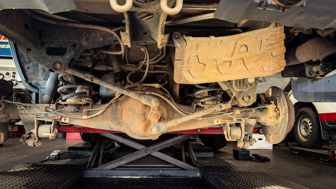 A car on a wheel alignment rack in a shop with sensors clamped to the wheels.