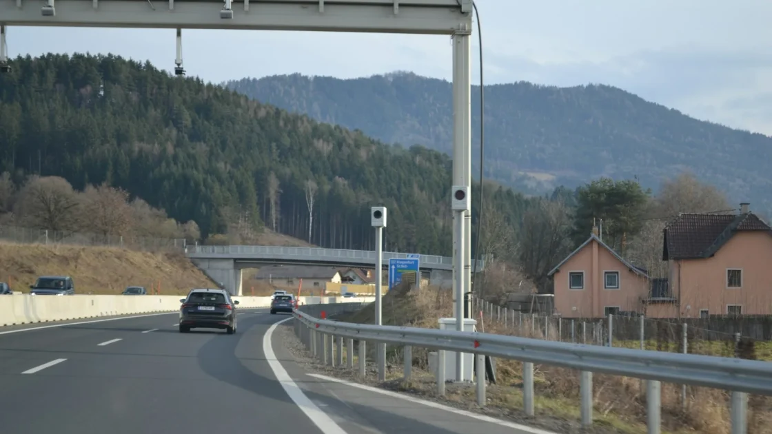 A forward-facing ADAS camera mounted at the top of a windshield behind the rearview mirror, aimed at painted lane lines on the road ahead.