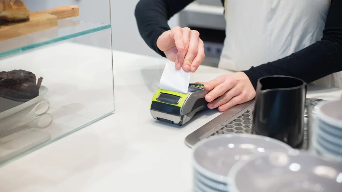 A service advisor reviewing an itemized calibration estimate with a customer at a repair shop counter.
