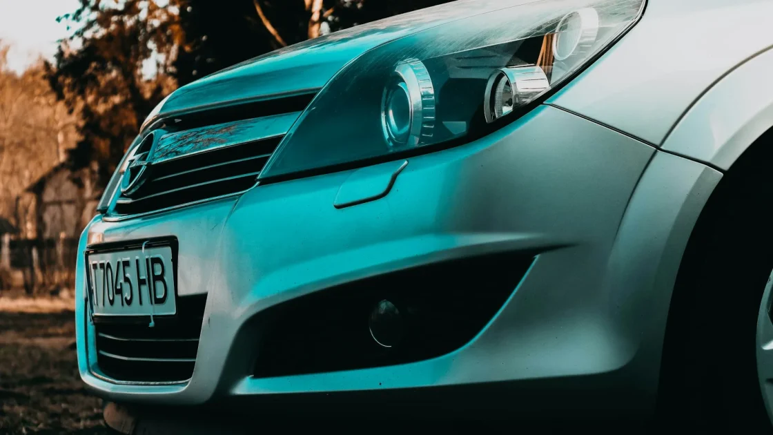 The lower front bumper of a car with a small square radar sensor panel visible behind the grille.