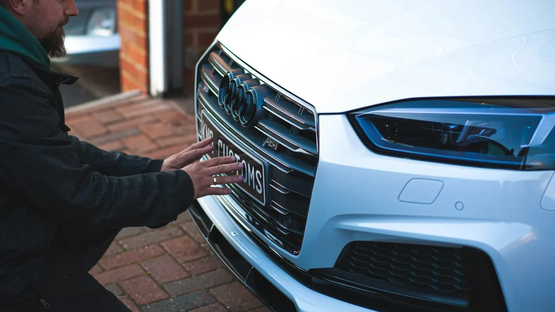 Close-up of a car front grille and bumper area where the forward collision radar sensor is hidden behind the emblem.