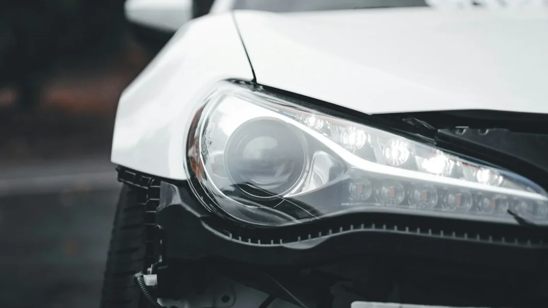 Front of a car braking on a city street with a radar sensor mounted behind the grille aimed at the road ahead.