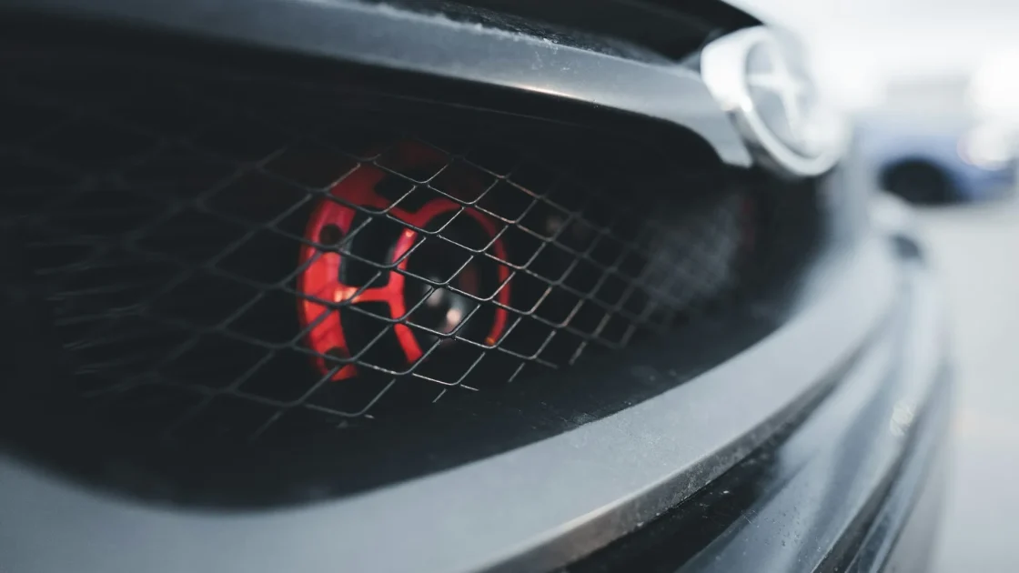 The front grille of a car with a radar sensor module hidden behind the emblem, aimed down the road ahead.