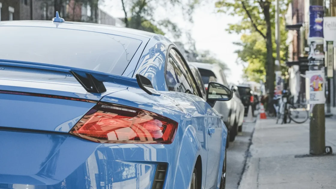 A close view of the round ultrasonic parking sensors set into a car's rear bumper near the license plate.