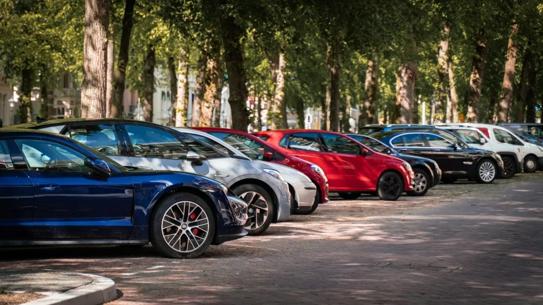 A row of late-model cars parked in a lot, each carrying forward cameras and bumper radar behind its trim.