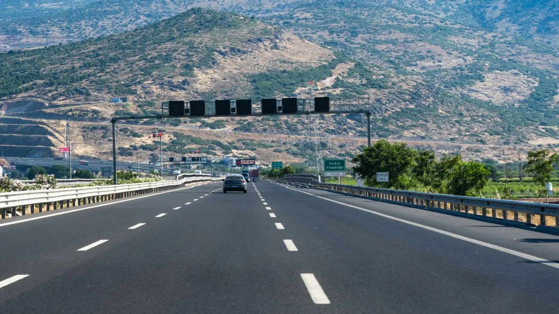 View through a car windshield on a highway showing a safe following gap to the vehicle ahead while adaptive cruise control is engaged.