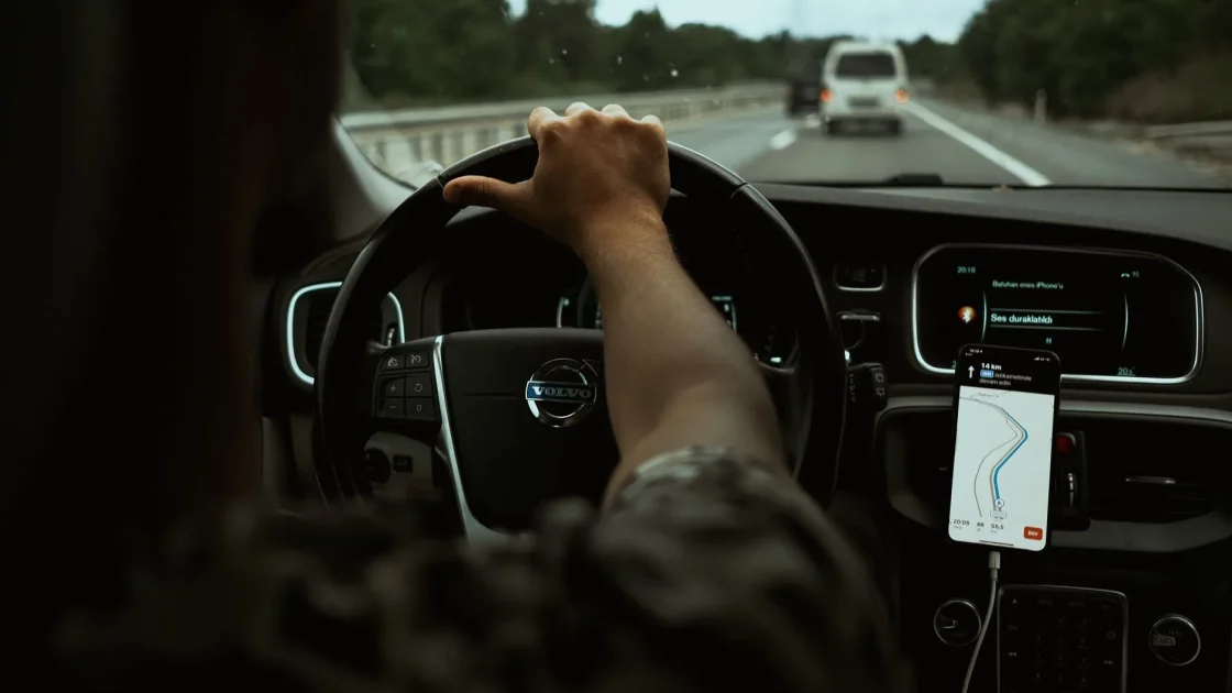 A modern car dashboard display showing active lane keeping and adaptive cruise control icons while driving on a highway.