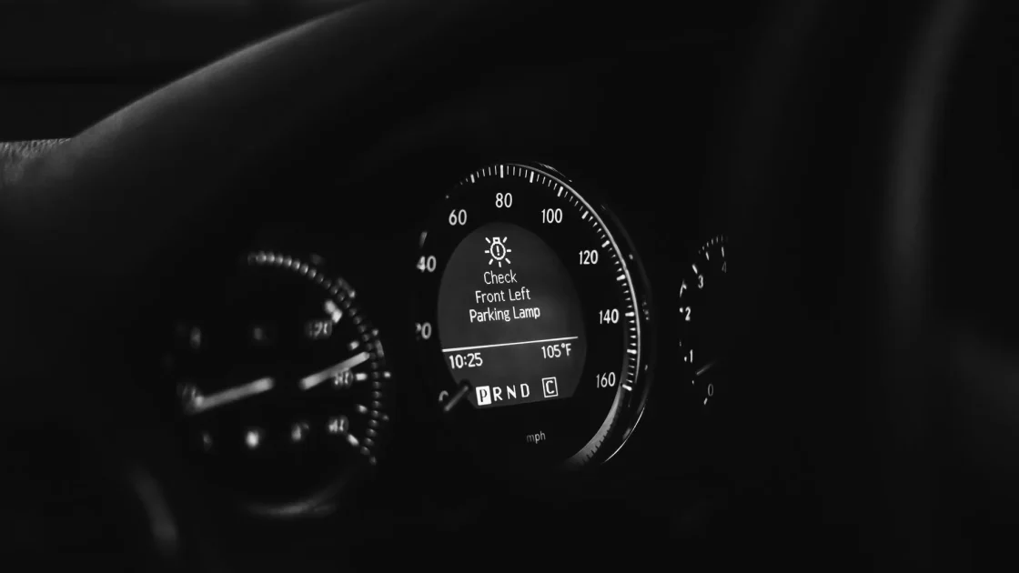 A car dashboard showing an amber driver-assist warning symbol illuminated behind the steering wheel.