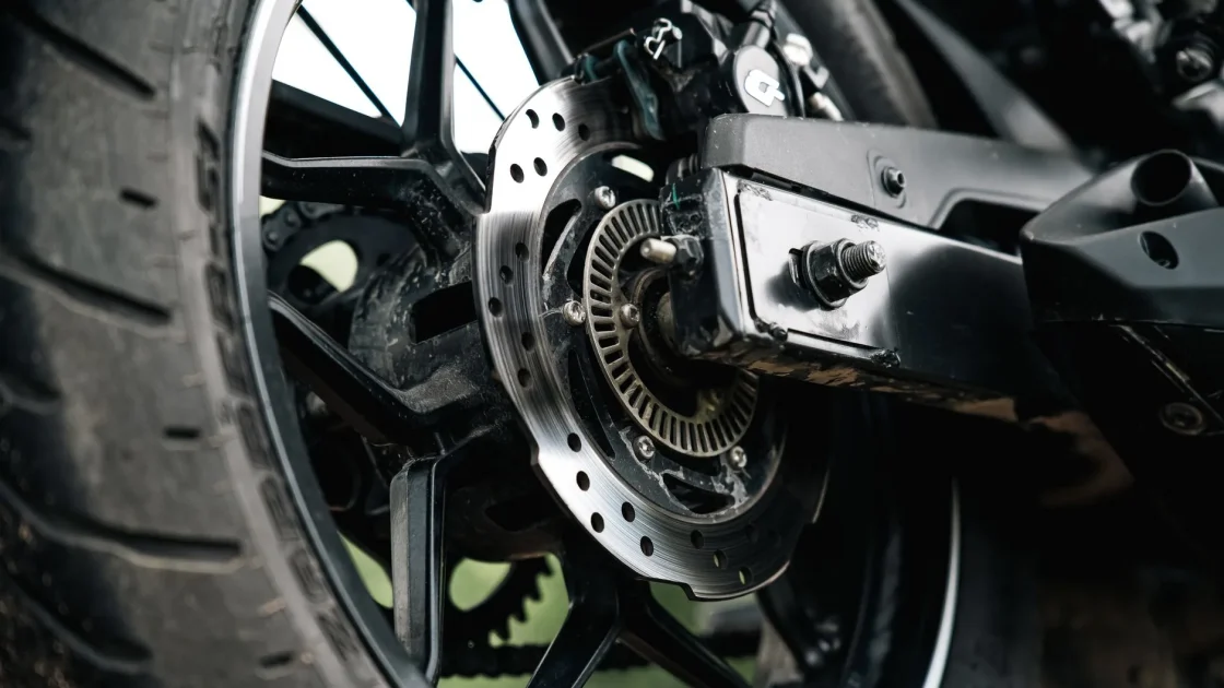 A close view of a motorcycle tail section with a small rear-facing radar module used for blind spot detection.