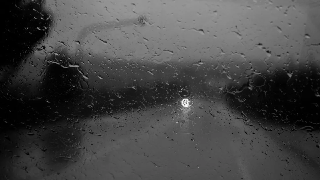 Rain beading on a car windshield in front of the forward camera housing that feeds the collision warning system