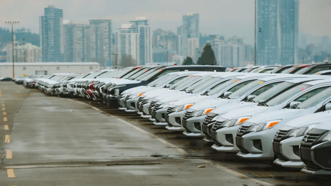 A row of late-model used cars on a dealership lot, several equipped with visible forward camera sensors and parking sensors.