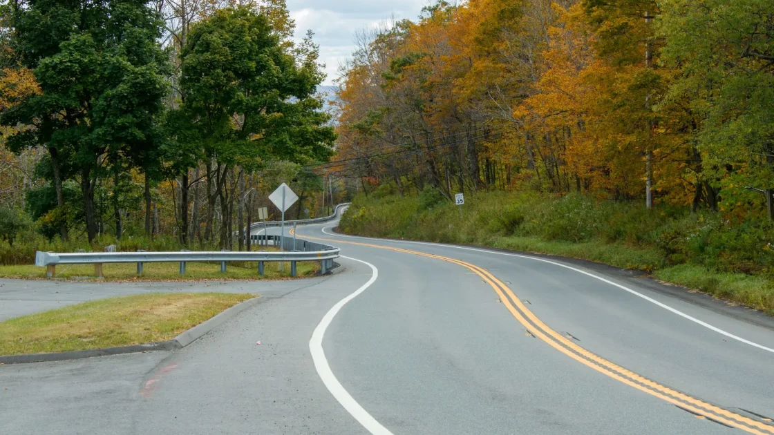 A car following the painted lane markings around a sweeping curve on a two-lane road, seen from behind through a gentle bend.