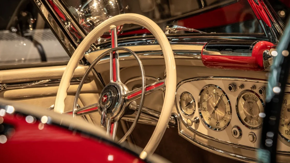 A driver's hands on a car steering wheel with the instrument cluster visible behind it.