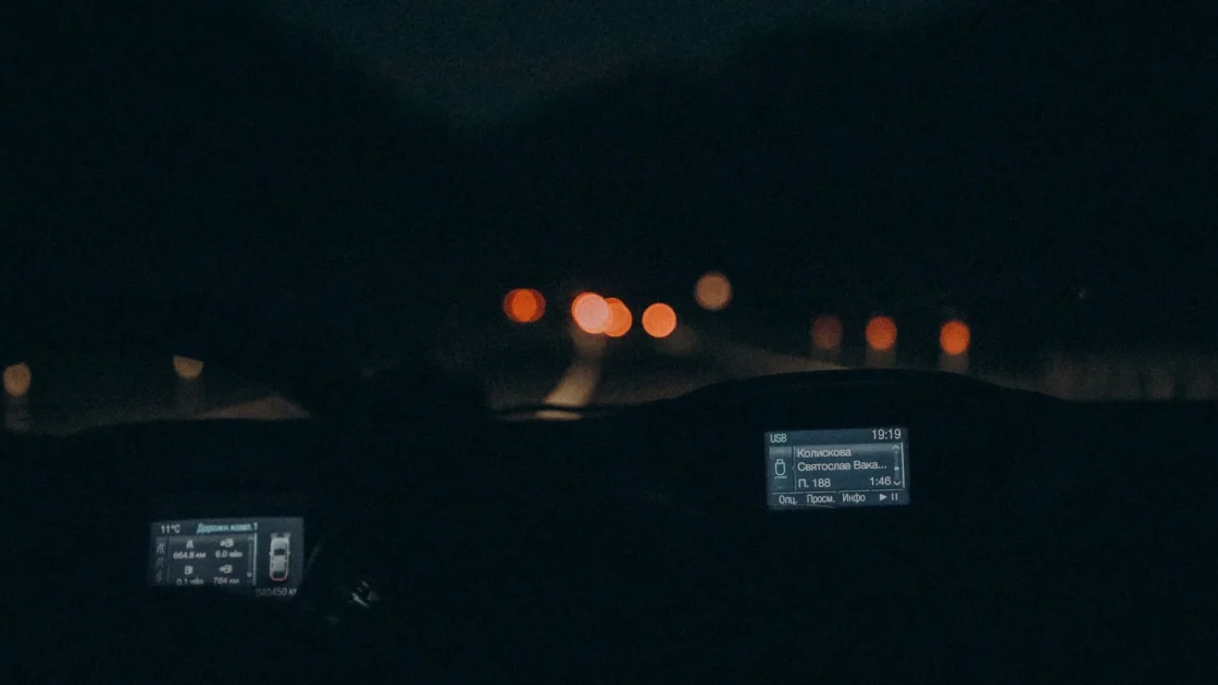 A car head-up display showing a thermal night vision image with a pedestrian glowing white on a dark road.